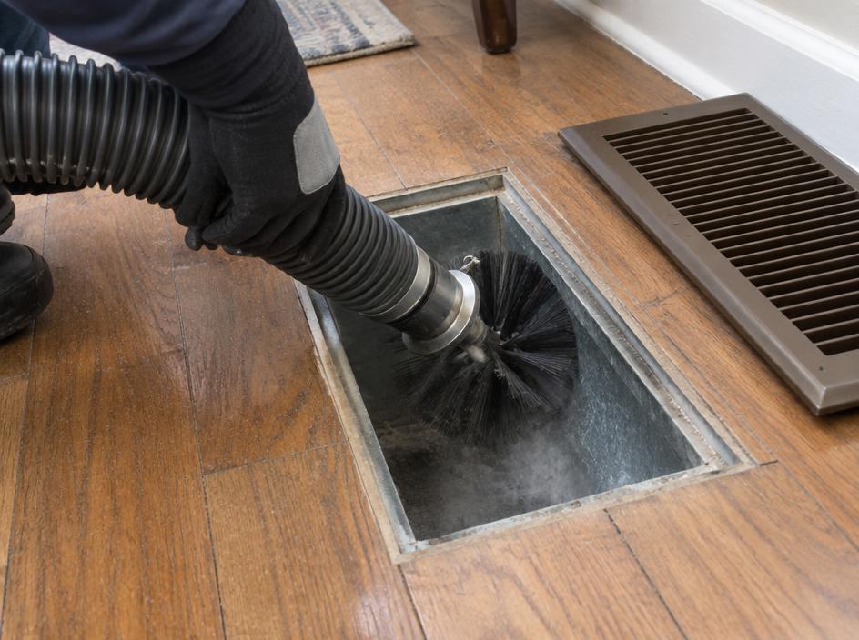 Rotary brush and HEPA vacuum hose cleaning a floor duct register